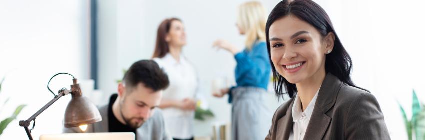 mulher com terno preto usando computador em um escritório com outras pessoas